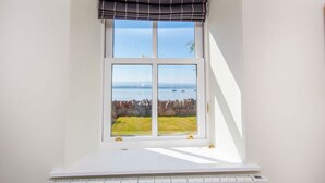 A room with a bay window overlooking a rocky coastline and the sea. - 2 bedroom accommodation in Fortrose (Fortrose)