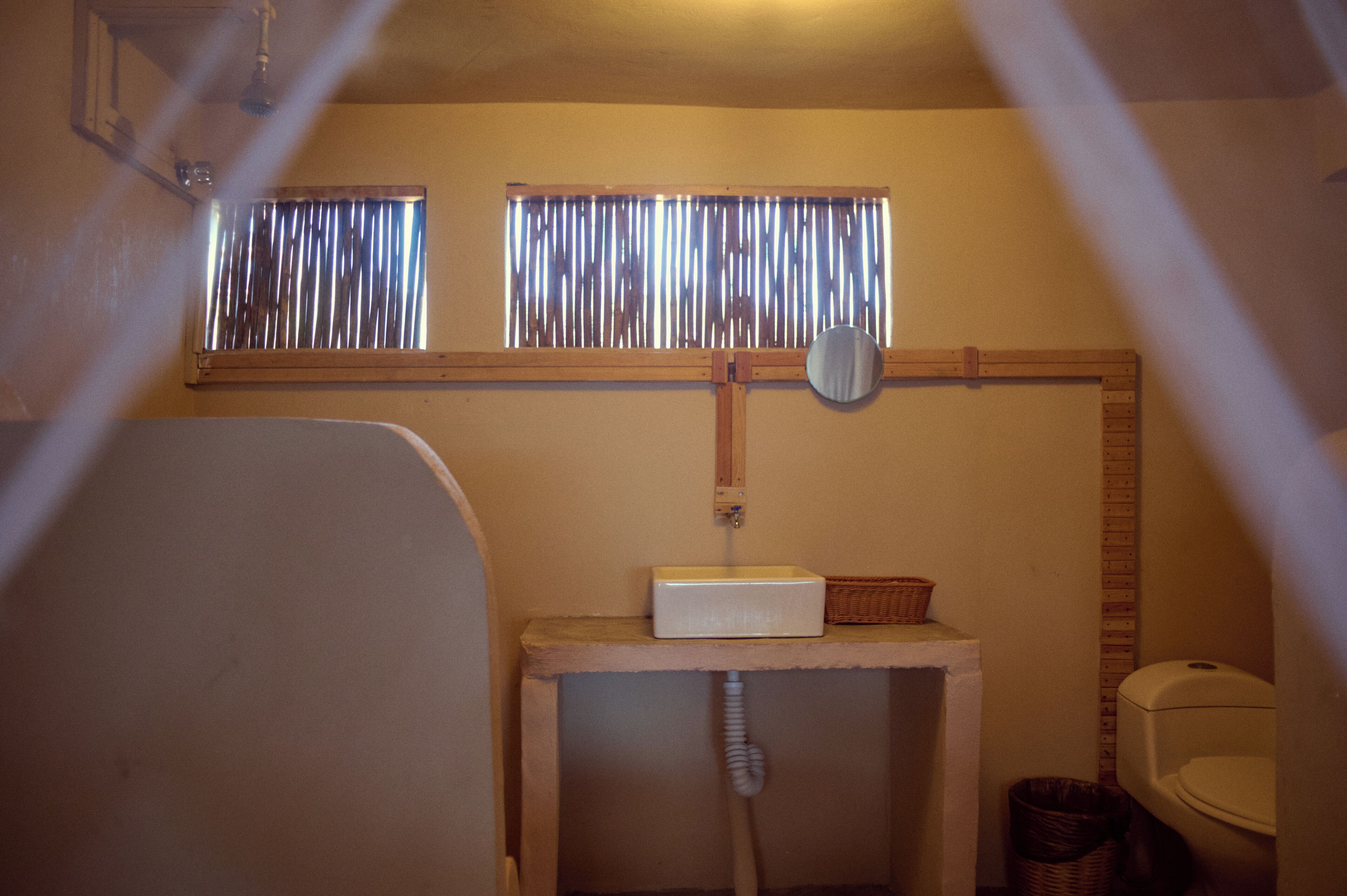 Een badkamer met een raam, een spiegel, een wastafel en een toilet.
