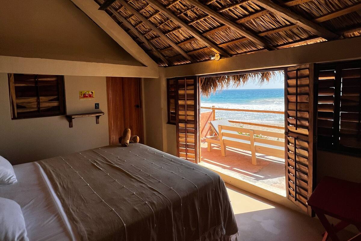 Une chambre avec un lit, un plafond en bois et une vue sur la plage.