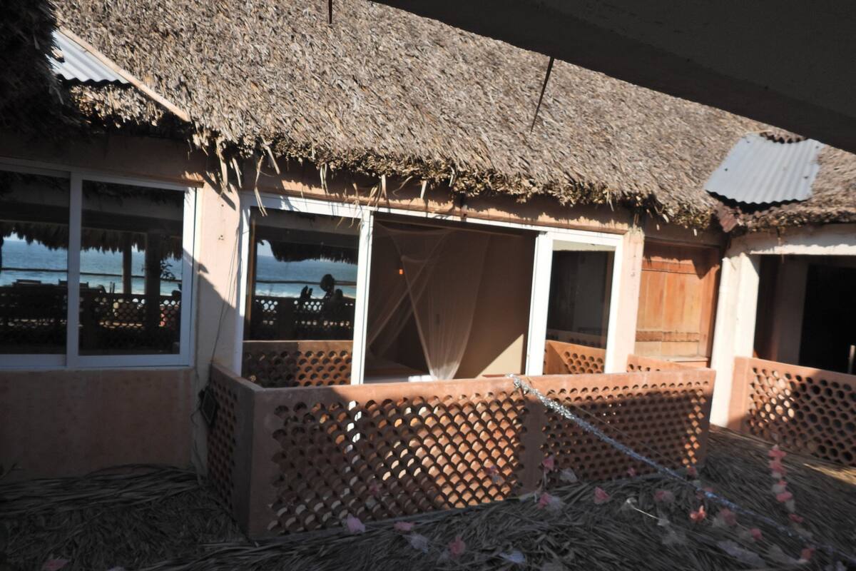 Une construction à toit de chaume, dotée de nombreuses fenêtres et d’une clôture en treillis.