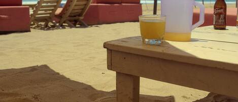 A beach setting with a table, a yellow umbrella, and beach chairs.