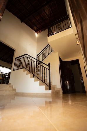 Una escalera con barandillas negras decoradas que sube a un segundo piso.