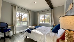 A bedroom with a bed, a desk, and two windows. - Creekside Cottage - Waterfront Retreat with Kayaks, Fishing & Game Room (Kingsville)