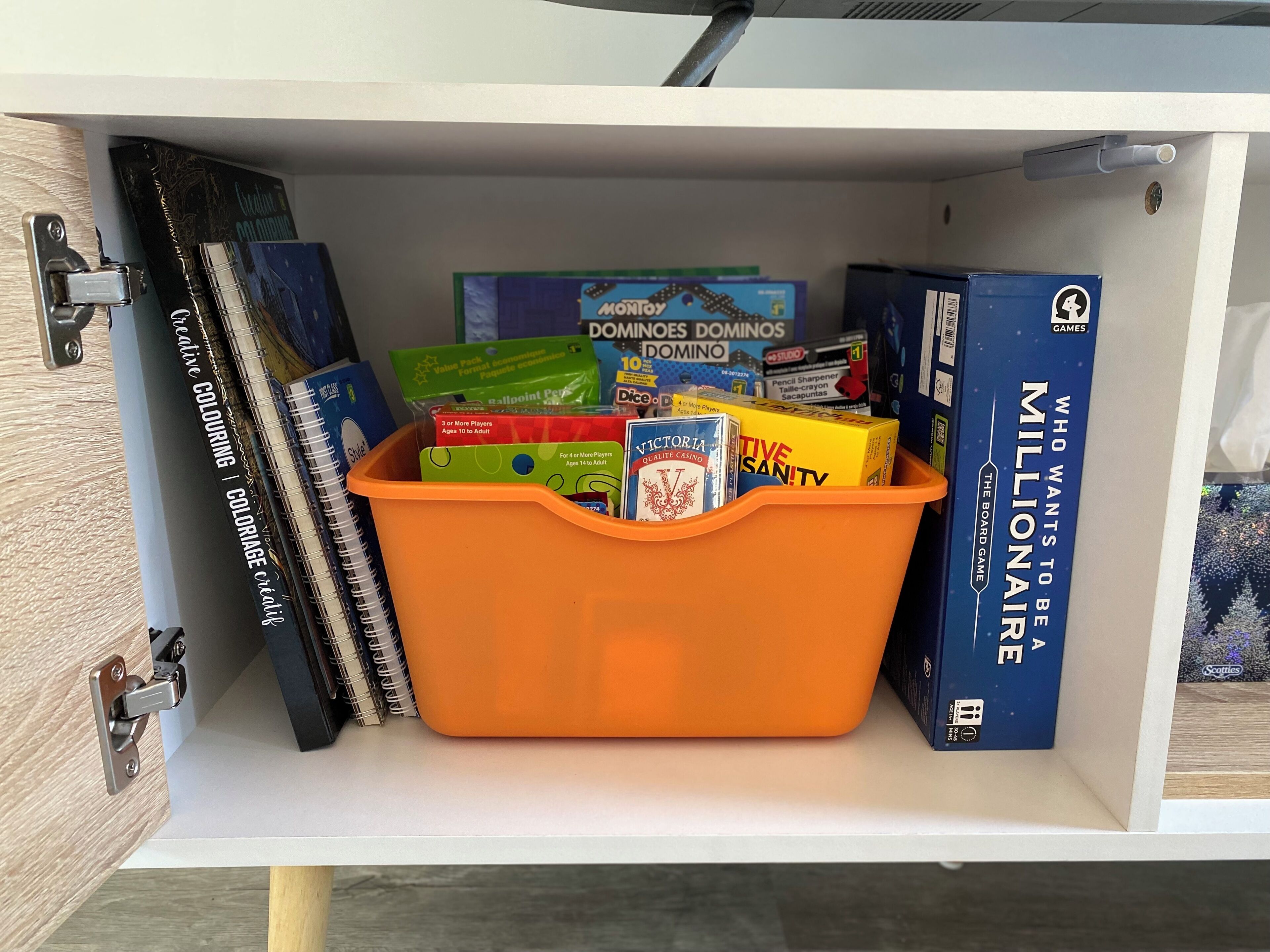A storage unit with a variety of board games and books.
