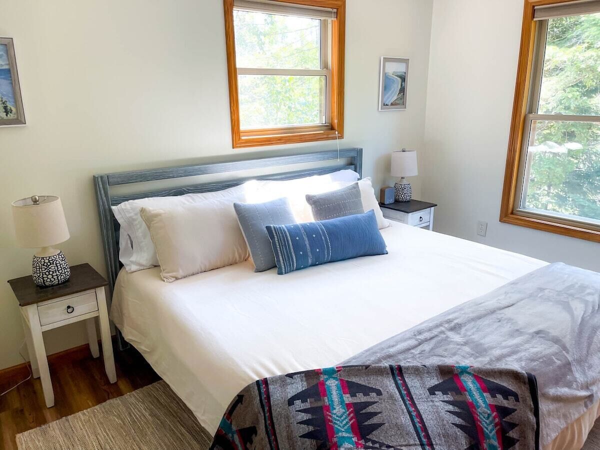 A bedroom with a bed, two bedside tables, a window, and a rug.