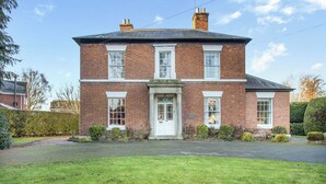 A two-story brick house with a front door, two windows on the ground floor, and a driveway. - 5 bedroom accommodation in Wem, near Shrewsbury (Wem, near Shrewsbury)