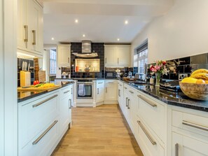 Una cucina moderna con mobili bianchi, un'isola centrale e un pannello di rivestimento nero.