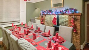 A dining room with a long table set for a meal, a fireplace with a Christmas garland, and a mirror on the wall. - 5 bedroom accommodation in Wem, near Shrewsbury (Wem, near Shrewsbury)