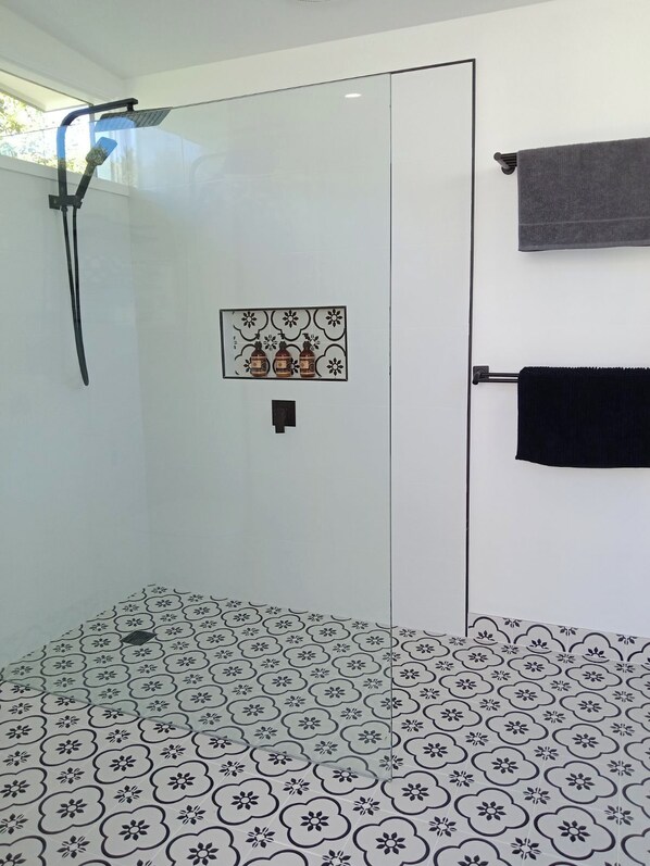 A modern bathroom with a glass shower enclosure, a decorative tile backsplash, and a towel rack. - Gabo Views waterfront. (Mallacoota)
