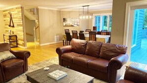 Un salon spacieux avec un canapé en cuir, une table basse et un coin repas comprenant des chaises et une table.