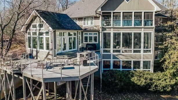 Een huis met een ruim terras en een balkon op de tweede verdieping.