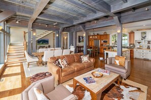 A spacious living area with a large brown leather sofa, a coffee table, and a dining area with white chairs. - Heaven On Earth ~ Wintergreen Mountain (Wintergreen Resort)