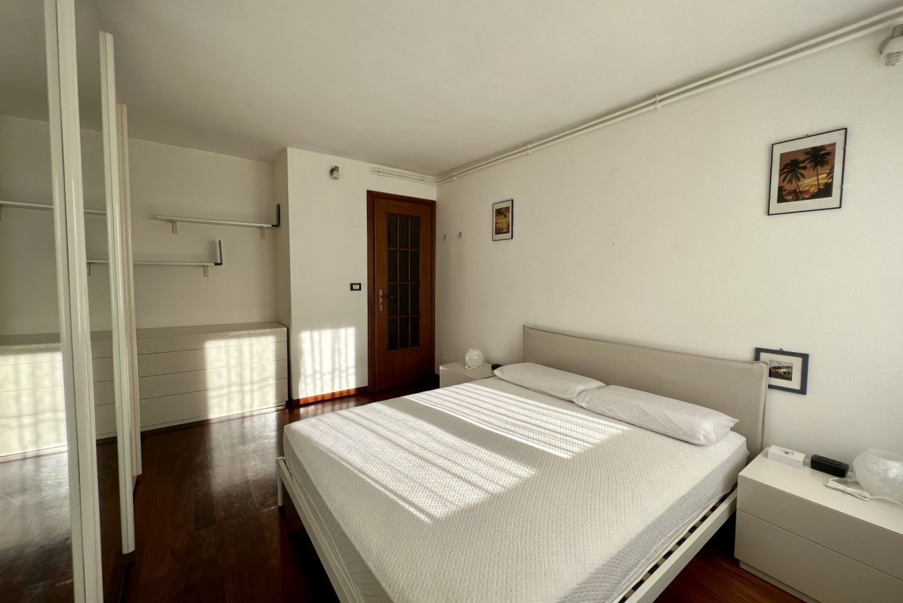 A bedroom with a bed, bedside tables, a door, and a small wall-mounted picture.