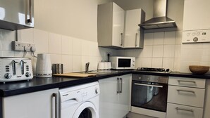 A modern kitchen with a washing machine, microwave, stove, and various appliances. - Stylish House in Sheffield (Sheffield)
