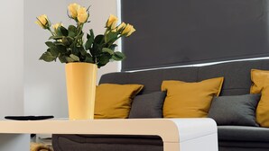 A modern living room with a sofa, yellow cushions, and a vase of yellow flowers on a white coffee table. - Stylish House in Sheffield (Sheffield)