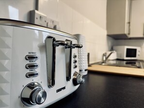 Un grille-pain blanc doté de boutons de réglage et de boutons indiquant les fonctions « DÉCONGÉLATION », « RÉCHAUFFAGE » et « ANNULATION ».