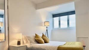 A bedroom with a bed, nightstands, a lamp, and a window. - Stylish House in Sheffield (Sheffield)