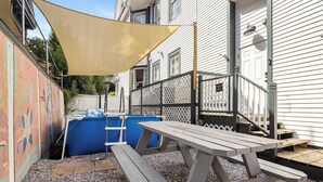 A patio area with a picnic table, a pool, and a fence.