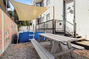 A patio area with a picnic table, a pool, and a fence. - Claiborne Guest House w/pool by Historic Getaways (New Orleans)