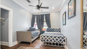 A bedroom with two beds, a ceiling fan, a window with curtains, and a rug on the floor.