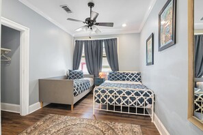 A bedroom with two beds, a ceiling fan, a window with curtains, and a rug on the floor. - Claiborne Guest House w/pool by Historic Getaways (New Orleans)