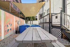 A wooden picnic table with a shade sail overhead, surrounded by a gravel area and a fence with a gate labeled 'Entrance for Unit B'. - Claiborne Guest House w/pool by Historic Getaways (New Orleans)