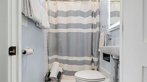 A bathroom with a striped shower curtain, a toilet, a sink, and a towel rack.