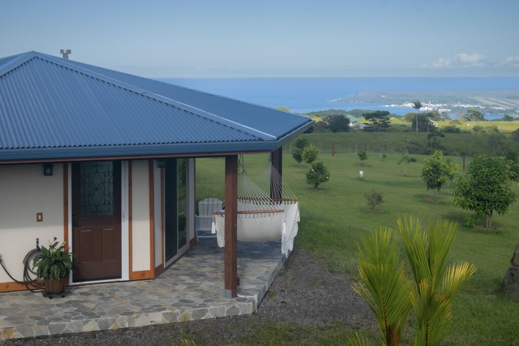 A house with a blue roof, a stone-paved porch, and a view of the ocean.