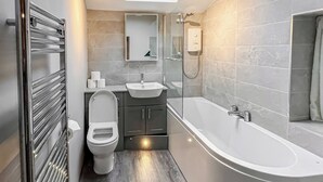Een moderne badkamer met toilet, wastafel en bad.