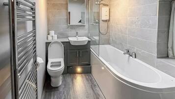A modern bathroom with a toilet, sink, and bathtub.