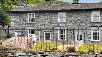 A stone house with multiple windows and a stone wall in front.