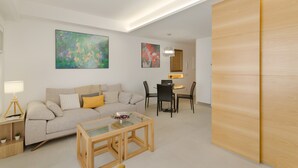 A modern living room with a sofa, coffee table, and dining area.