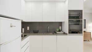 A modern kitchen with white cabinetry, a built-in oven, and a sink.