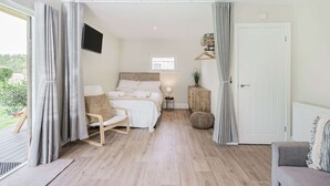 Une chambre à coucher avec un lit, une table de chevet, une lampe et une vue sur l’extérieur.