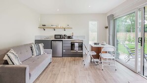 Une cuisine moderne avec un canapé gris, une table à manger et une porte-fenêtre coulissante donnant sur un balcon.