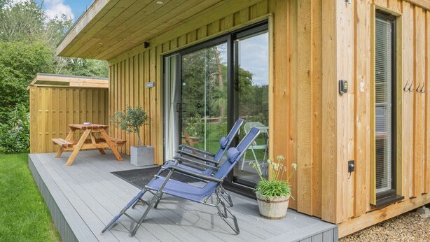 Une terrasse en bois avec une table de pique-nique et des chaises longues.