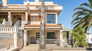 A two-story house with a balcony, a staircase, and a pool.