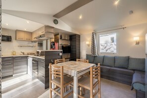 A compact kitchen with a dining area, a sofa, and a window with a view.
