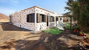 A house with a stone-patterned exterior, a patio with outdoor furniture, and a small garden area.