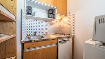 Une cuisine compacte avec des meubles en bois, un évier encastré, un lave-vaisselle et un four à micro-ondes.