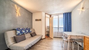 A modern living room with a sofa, dining table, and a 'HOME' sign on the wall. - Studio Apartment 'Samoens 1600' with Balcony (Samoëns)