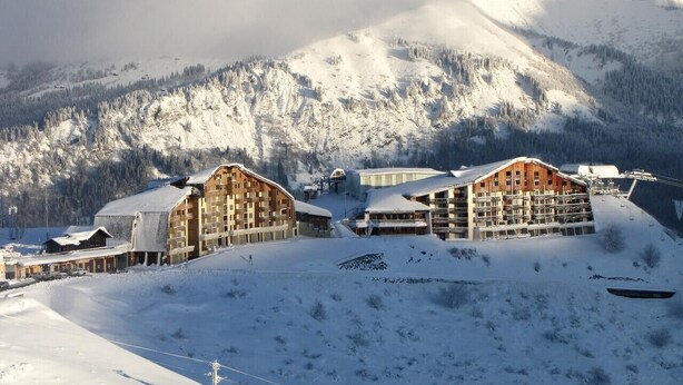 A snow-covered mountain resort with multiple buildings, including a large lodge and smaller structures, set against a backdrop of snow-capped peaks. - Studio Apartment 'Samoens 1600' with Balcony (Samoëns)