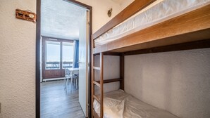 A bunk bed room with a wooden headboard, a small table, and a chair in the background. - Studio Apartment 'Samoens 1600' with Balcony (Samoëns)