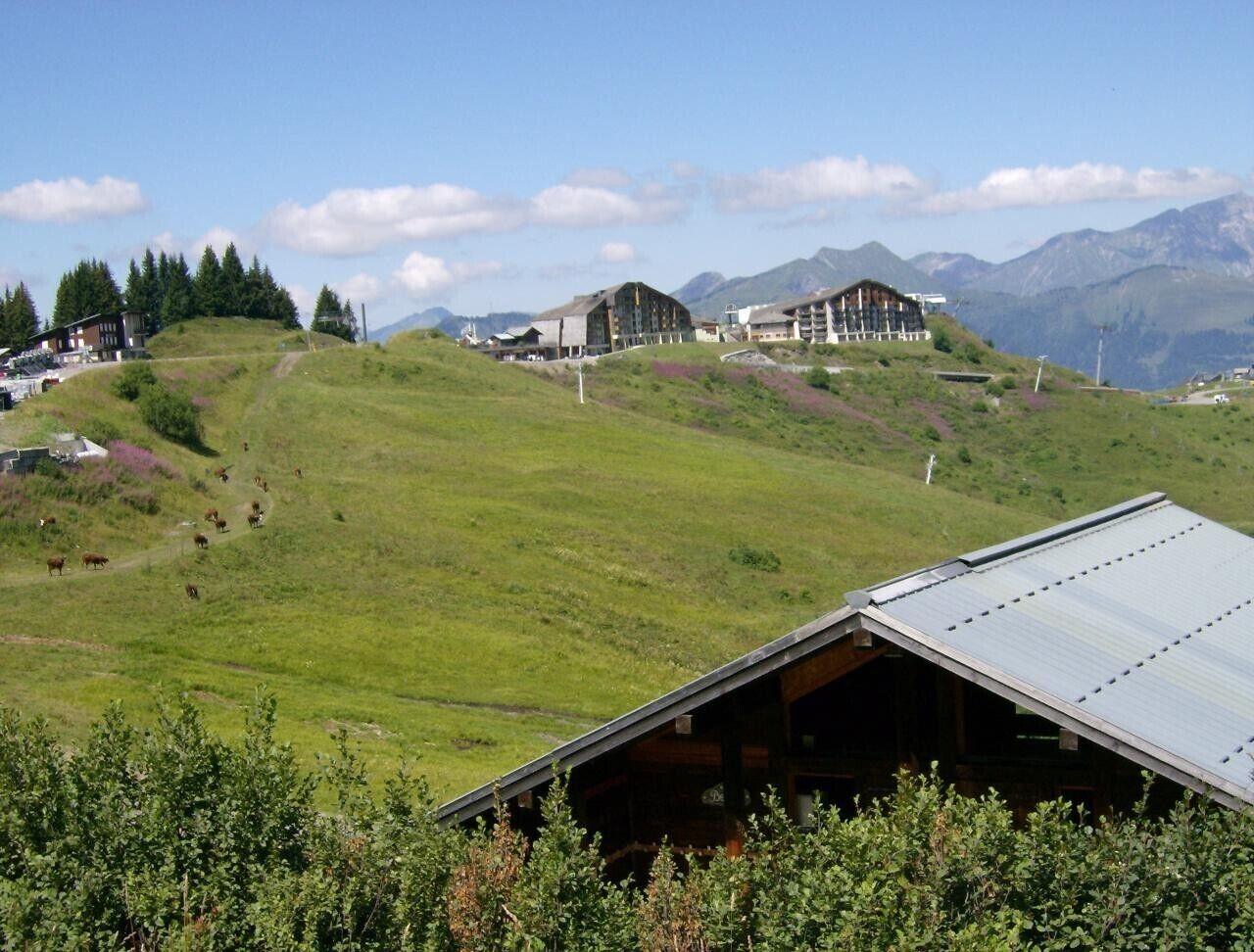 A mountainous landscape with a building complex, including a large structure with a sloped roof and smaller buildings.