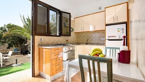 Eine Küche mit Kochinsel, Esstisch und Blick ins Freie.