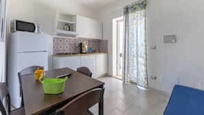Una cocina equipada con microondas, estufa y una mesa de comedor con sillas.