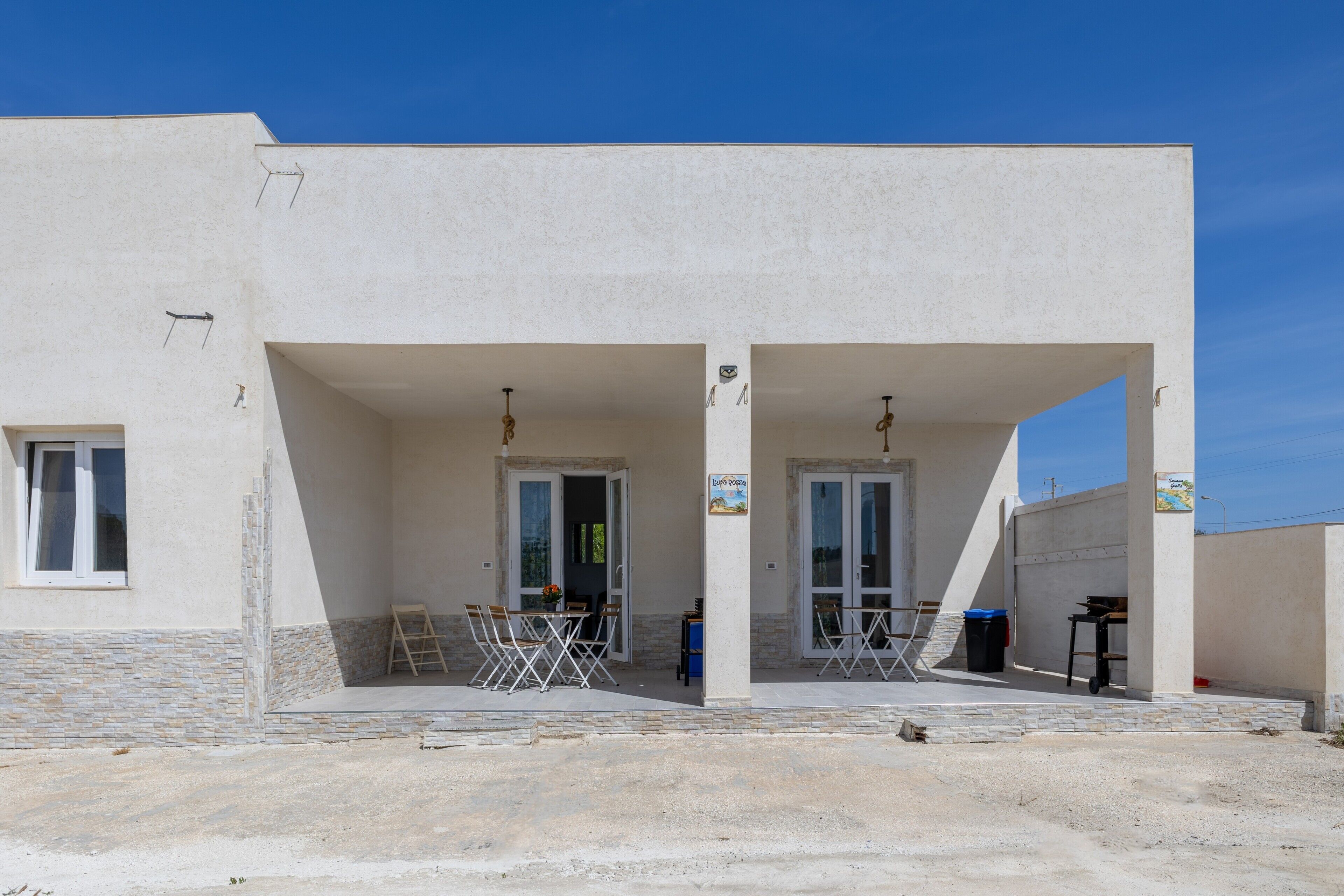 A building with two covered entrances, a table with chairs, and a ladder.