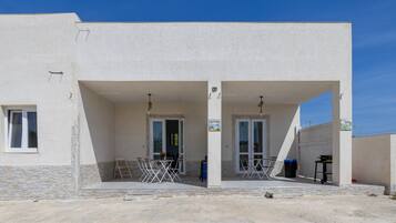 A building with two covered entrances, a table with chairs, and a ladder.