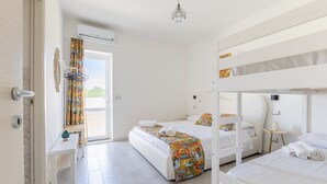 Habitación de hotel con literas, una mesita de noche pequeña, una ventana con cortinas y un equipo de aire acondicionado.