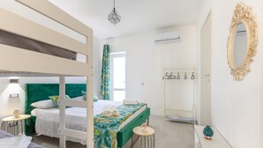 Una habitación de hotel con literas, una mesita redonda pequeña, un tocador con espejo y un perchero.